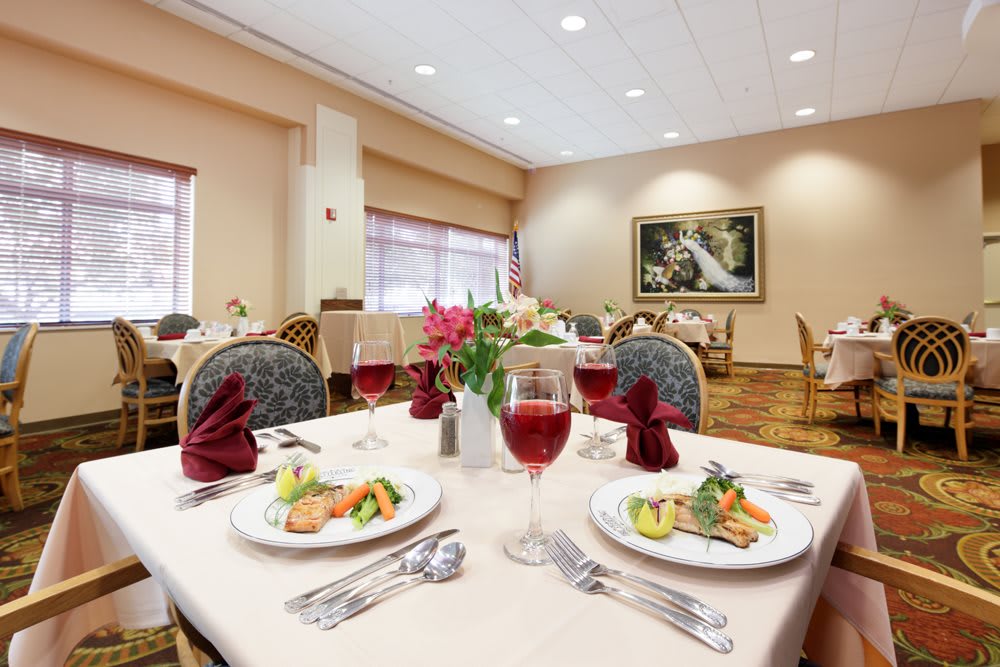 Elegant dining room with beautifully set tables, featuring dishes and wine glasses.