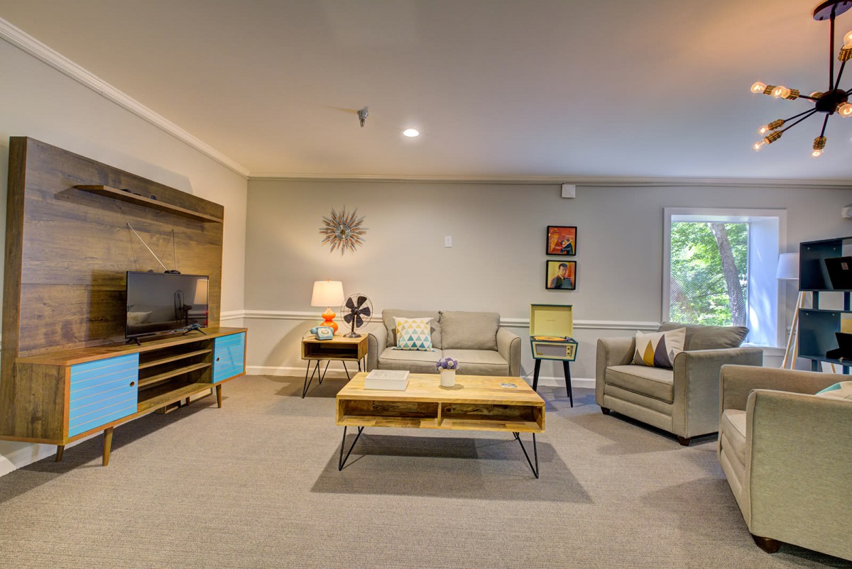 A modern living room featuring a cozy sofa, armchair, and a stylish coffee table with a TV stand in the background.