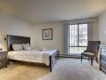 A minimalist bedroom with a bed, chair, and large window.
