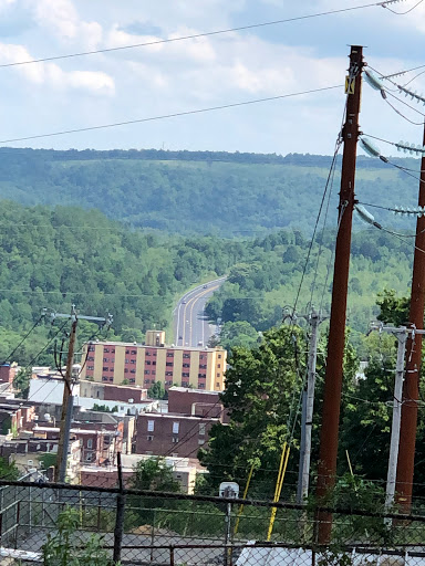 A view of a winding road leading through lush hills, with a town nestled below.