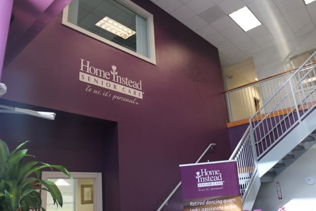 Interior view of an office with signage and stairs, featuring a purple wall.