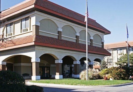 A two-story building with a flagpole and landscaped surroundings.