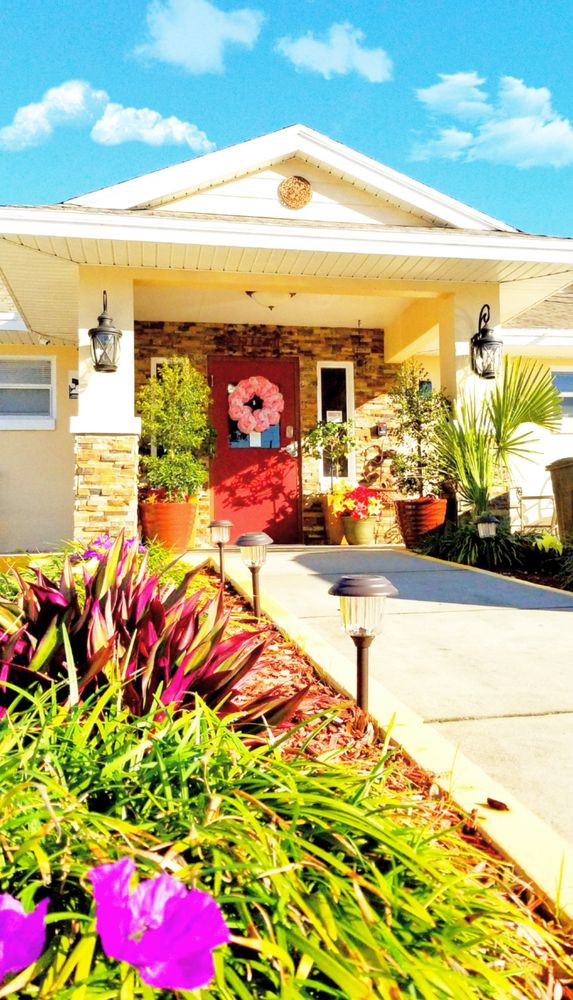 A cozy house entrance with decorative plants and a vibrant red door.