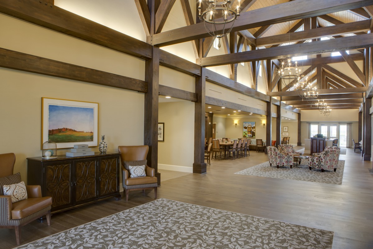 A spacious lobby with wooden beams, elegant furniture, and a decorative chandelier.