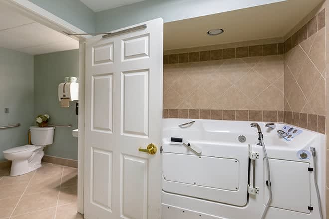 A bathroom featuring a walk-in tub with a partially open door.