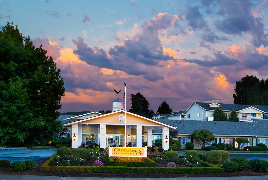 A charming building with a sign and flagpole stands against a backdrop of colorful sunset clouds.