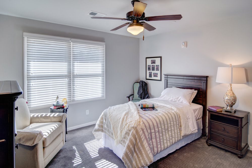 A cozy bedroom with a single bed, ceiling fan, and a window allowing natural light.