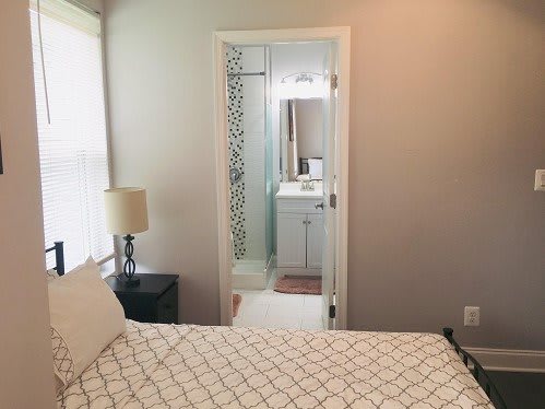 A cozy bedroom with an adjoining bathroom, featuring modern decor and soft lighting.