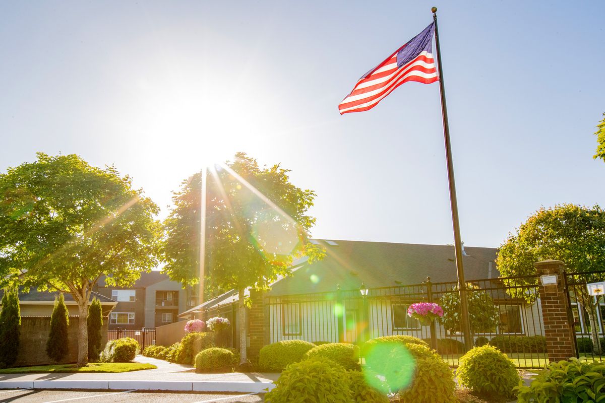 A bright sunny day with an American flag waving in front of a building.