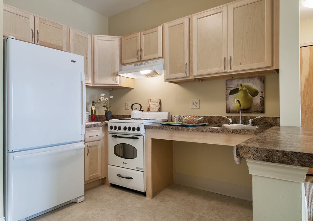 A modern kitchen featuring a refrigerator, stove, and wooden cabinets.