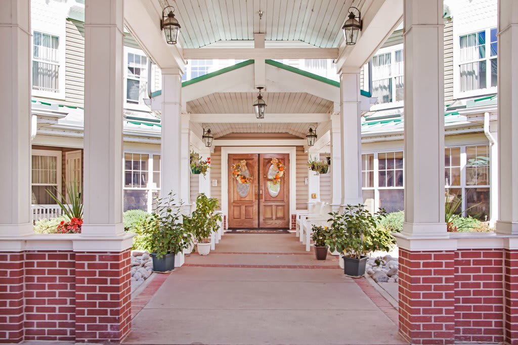 A welcoming entrance with wooden double doors, flanked by columns and decorated with hanging lanterns and potted plants.
