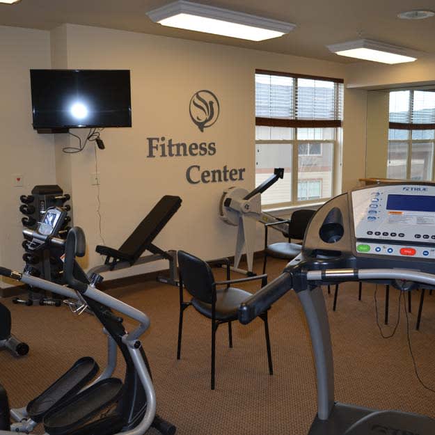 A fitness center with various gym equipment including treadmills, an exercise bike, and weights.