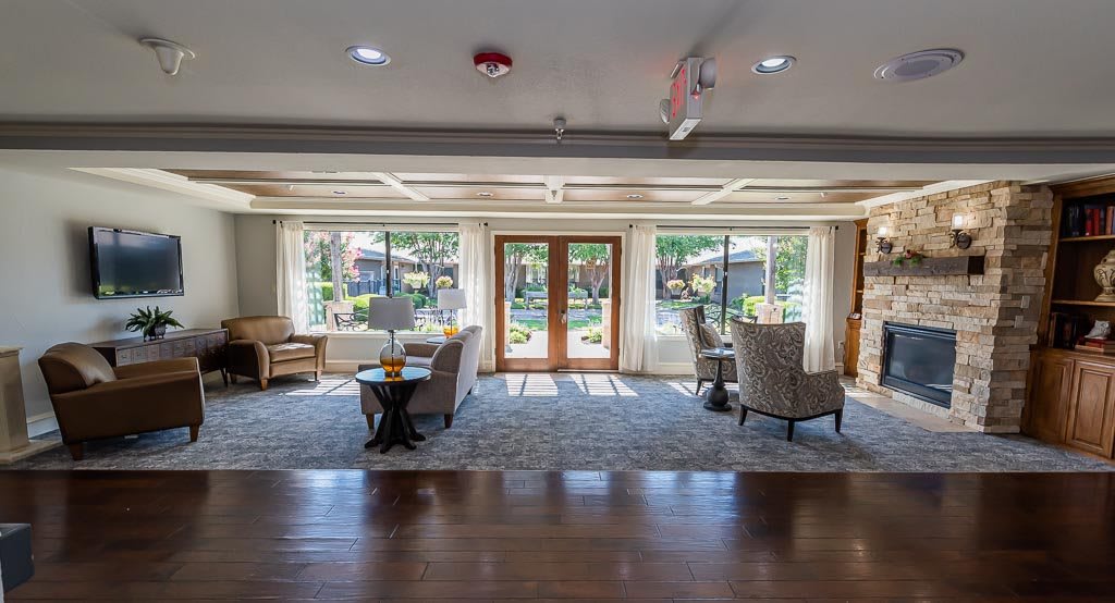 A spacious and well-lit lobby with comfortable seating and large windows overlooking a garden.