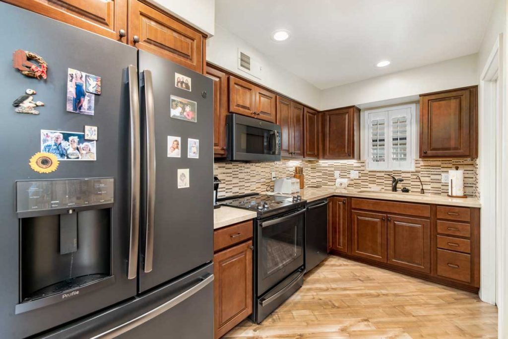 A modern kitchen with dark wooden cabinets and stainless steel appliances.