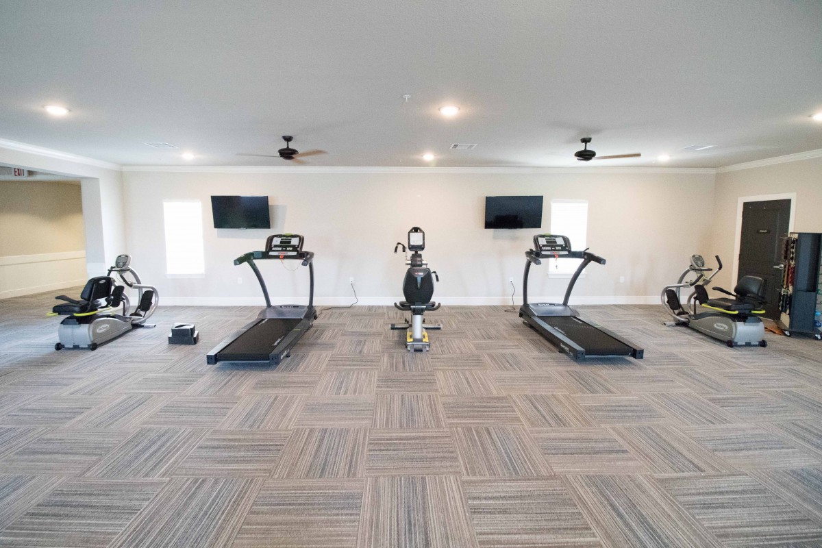 A modern gym equipped with treadmills, a stationary bike, and televisions.