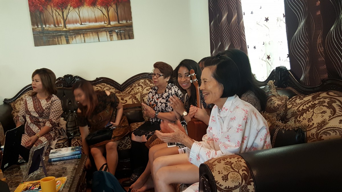 A group of people sitting in a living room engaged in conversation.