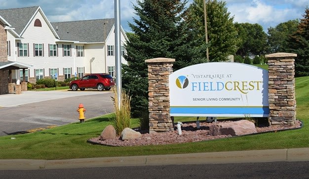 Entrance sign for Fieldcrest community with landscaped surroundings and residential buildings.