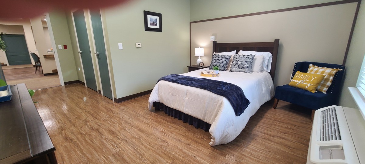 A cozy bedroom with a neatly made bed, stylish pillows, and a bedside lamp.