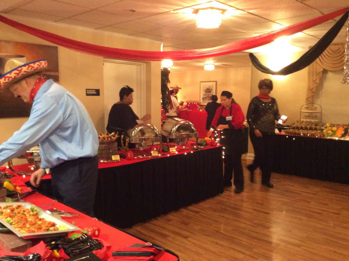A buffet setup at a themed event with people serving food from a decorated table.