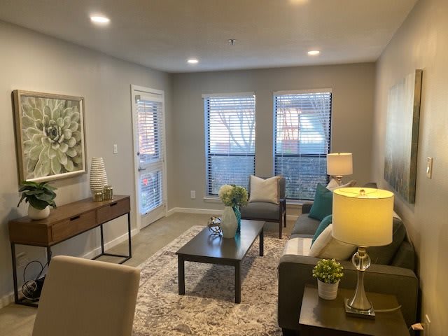 A cozy living room with modern decor featuring a sofa, coffee table, lamps, and wall art.