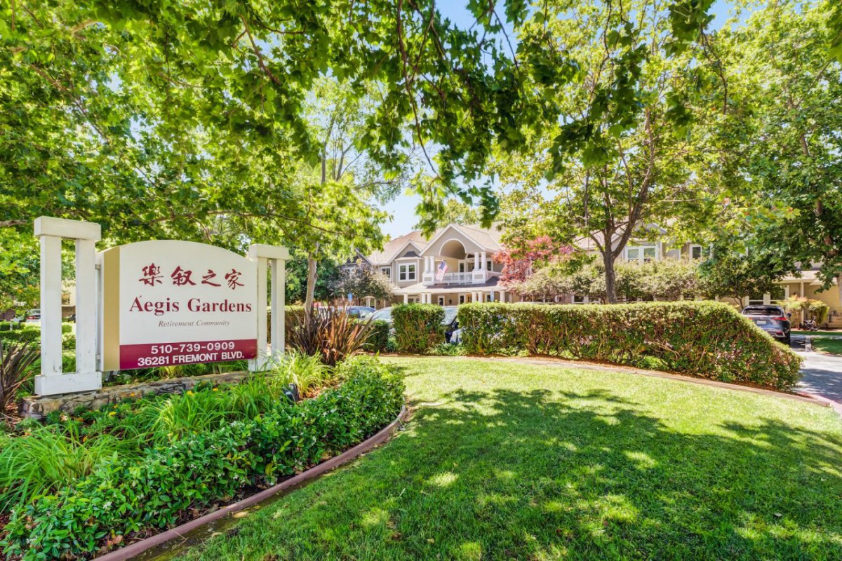 A well-maintained suburban property with lush landscaping and a welcoming entrance sign.