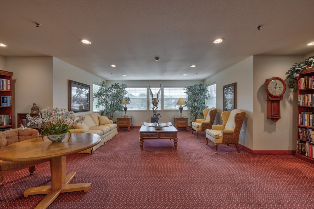 A cozy living room with sofas, armchairs, a coffee table, and large windows.