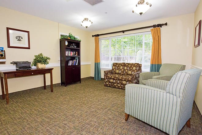 A cozy living room with comfortable seating and a bookshelf by the window.