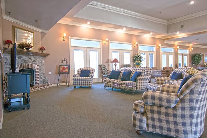 A spacious living room with plaid upholstered furniture and large windows.