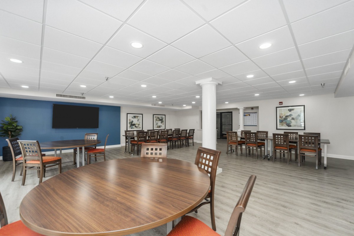 A spacious dining area with multiple tables and chairs, featuring modern decor and bright lighting.