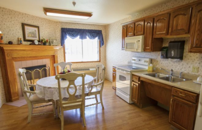 A cozy kitchen with a dining area, featuring wooden cabinets and a fireplace.
