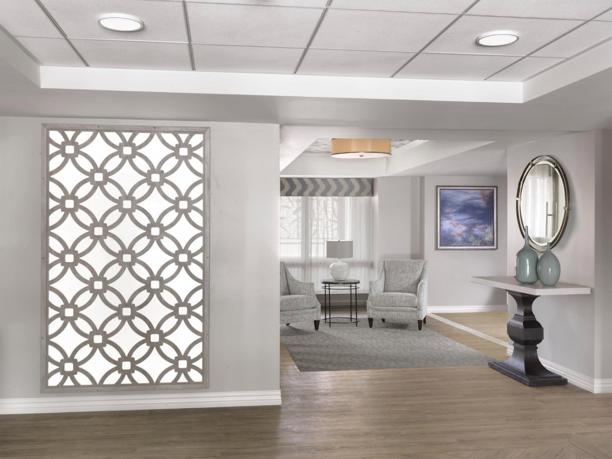 A modern lobby interior with a decorative wall, seating area, and neutral color palette.