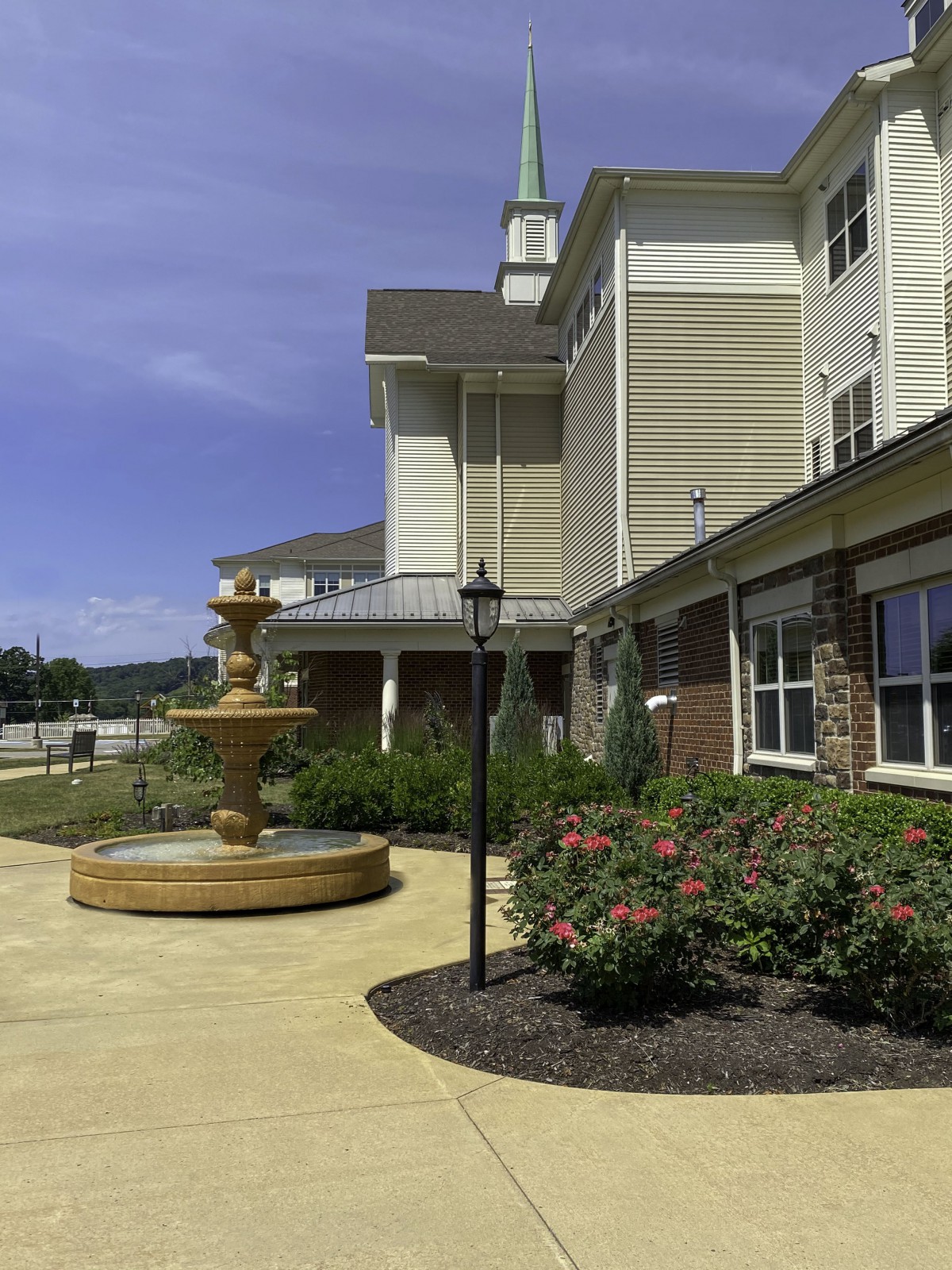 A scenic outdoor view of a building with a fountain and well-maintained garden.