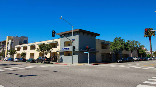 A modern commercial building at a street intersection under a clear blue sky.