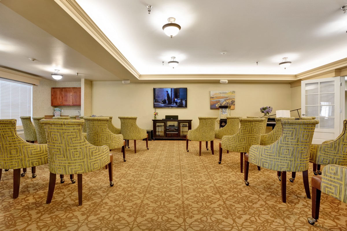 An empty conference room featuring upholstered chairs facing a television.