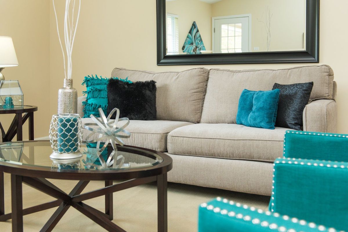A cozy living room featuring a beige sofa adorned with teal pillows and a stylish coffee table.