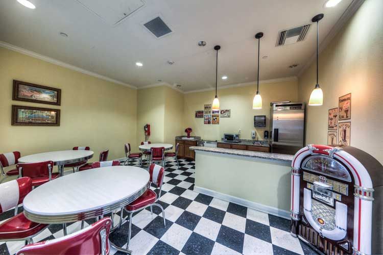 A retro-style diner with checkered flooring, red chairs, and pendant lighting.