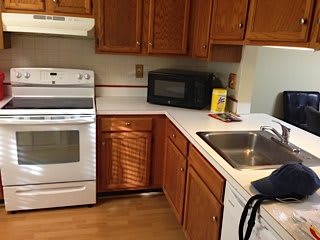 A kitchen with a stove, microwave, and sink surrounded by wooden cabinets.