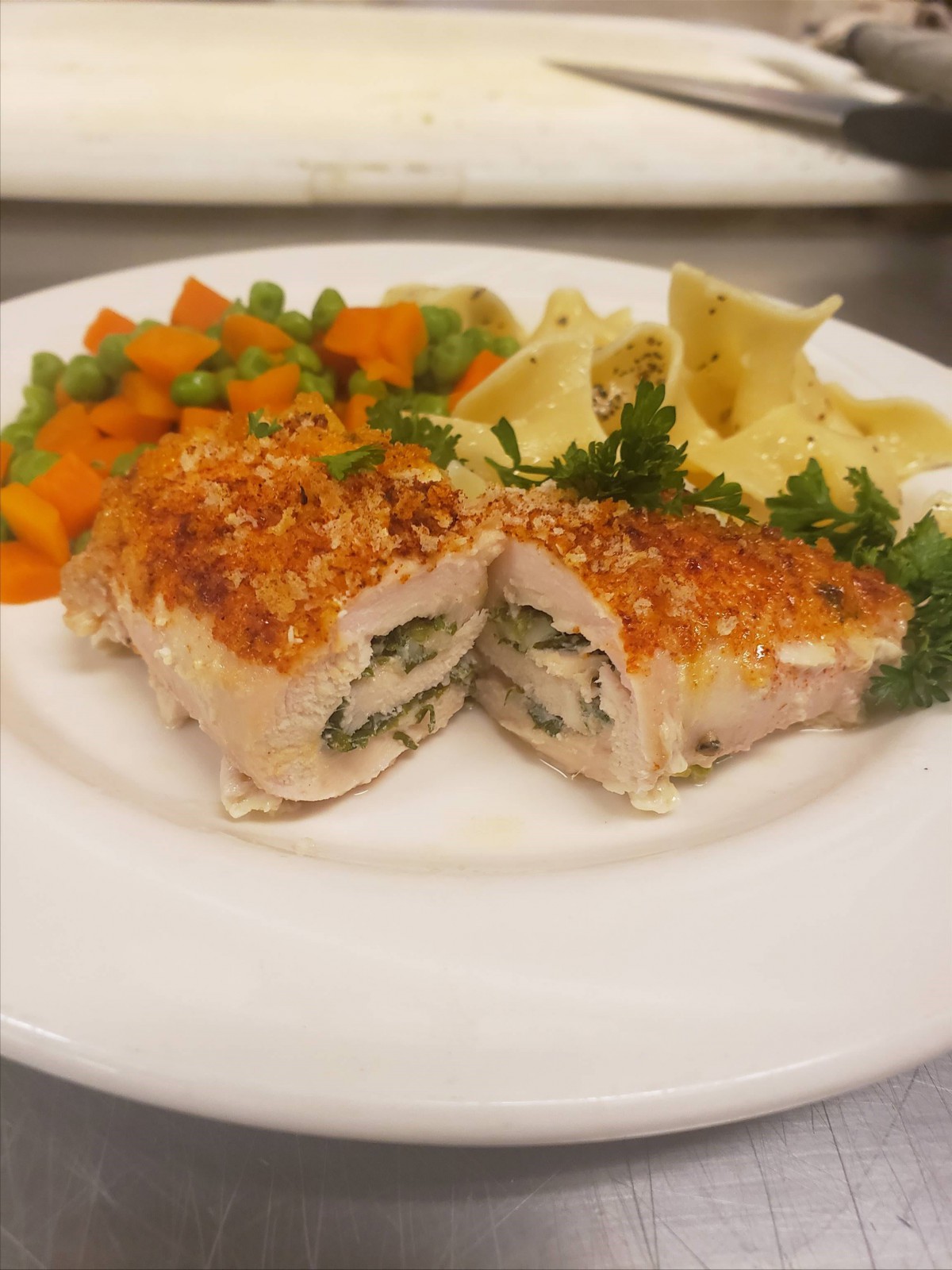 A gourmet meal featuring stuffed chicken breast, served with a side of pasta and mixed vegetables.