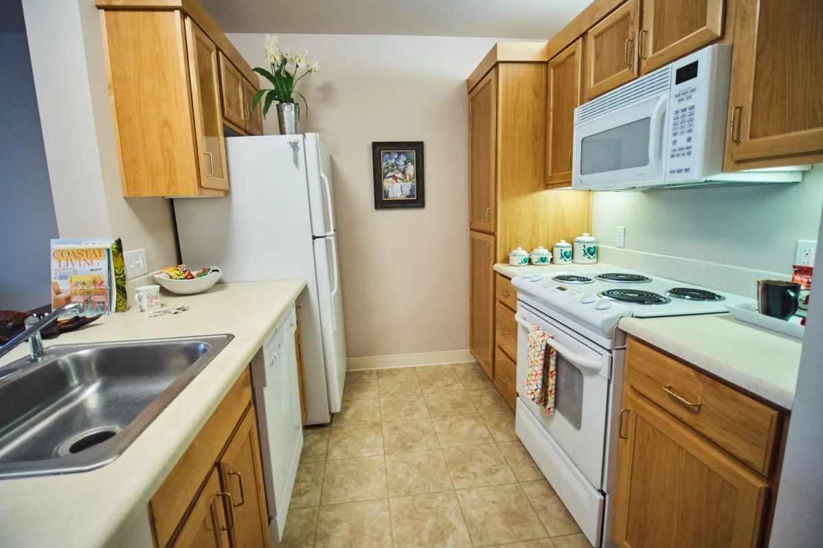 A compact kitchen with wooden cabinets, appliances, and countertops.