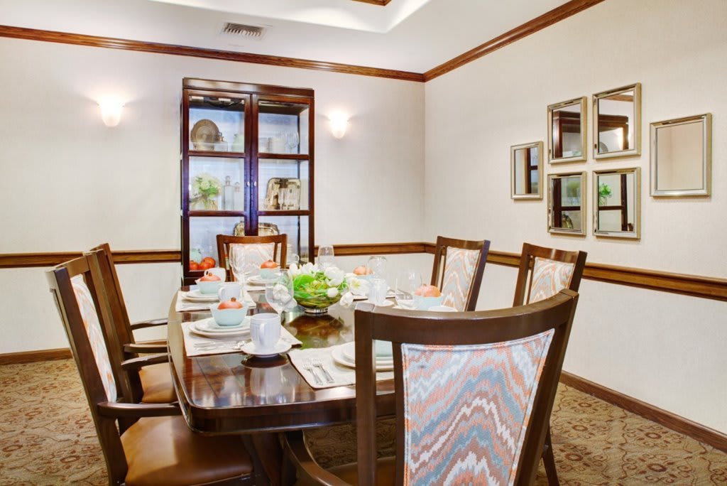 An elegant dining room with a set table and plush chairs.