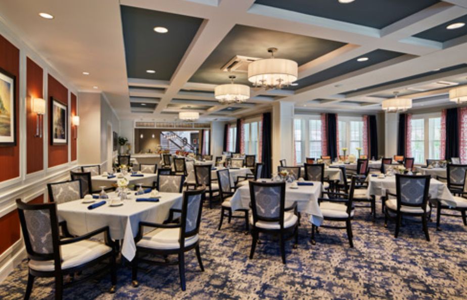 An elegant restaurant dining area with neatly arranged tables and chairs under stylish chandeliers.