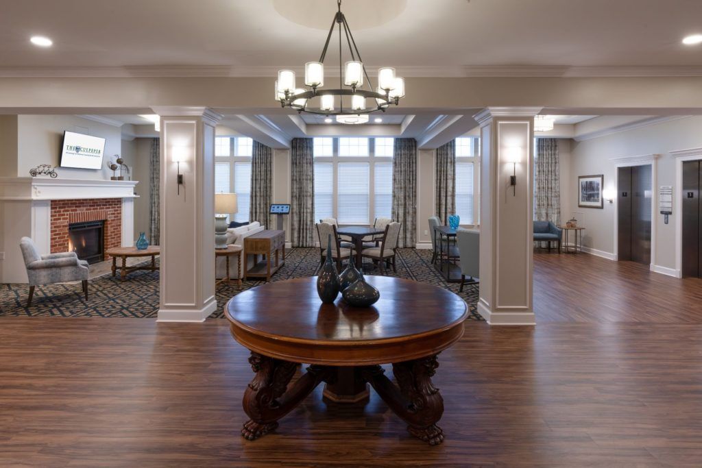 A spacious and elegantly decorated living room with a central wooden table and chandelier.