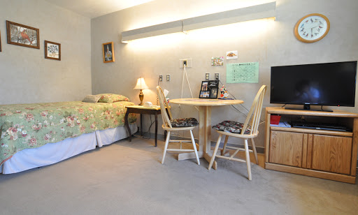 A cozy and well-lit bedroom featuring a bed, a small dining area with chairs and a table, and a television.