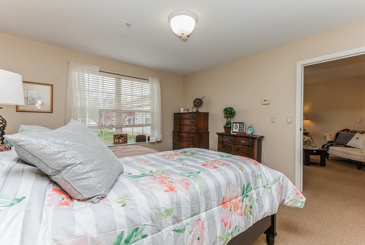 A cozy bedroom with a floral bedspread and natural lighting.