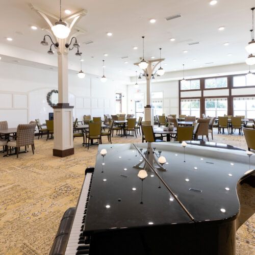A spacious dining area with a grand piano, featuring modern furniture and elegant lighting fixtures.