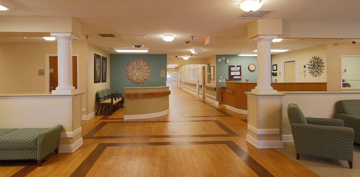 A well-lit corridor in a healthcare facility, featuring a reception desk and seating area.