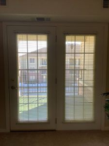 A pair of French doors with blinds, offering a view of the backyard.