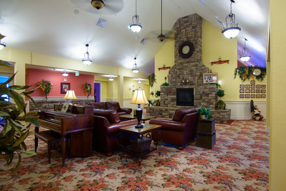 A cozy interior lounge area with a vintage design, featuring a stone fireplace, plush seating, and warm lighting.