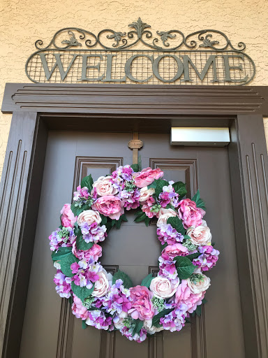 A charming entrance adorned with a floral wreath and a warm welcome sign.