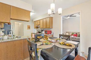 A modern kitchen and dining area with wood cabinets and a stylish table setting.